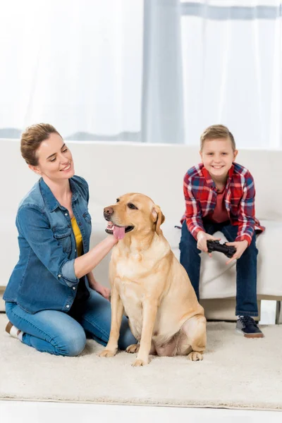 Glückliche Mutter streichelt Hund, während Sohn Videospiele spielt — Stockfoto