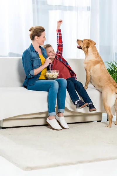 Mãe e filho alimentando seu cão com pipocas — Fotografia de Stock