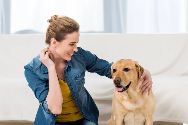 Woman petting her labrador dog at home — Stock Photo