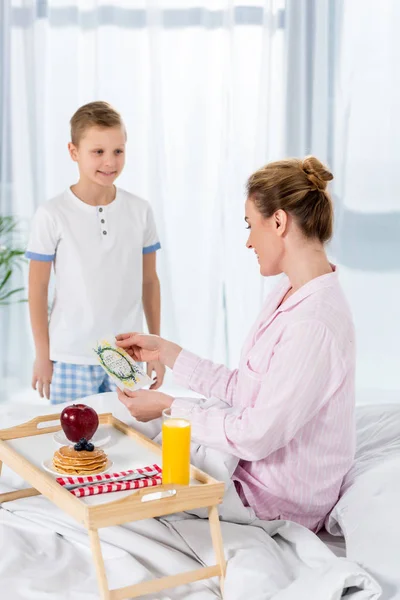 Little son giving breakfast in bed for mother on mothers day — Stock Photo
