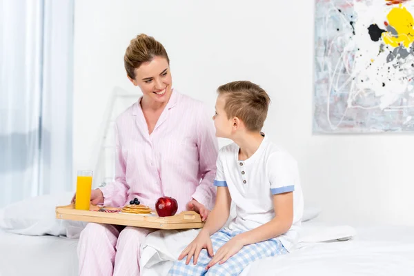Mother holding breakfast on wooden tray made by her son — Stock Photo