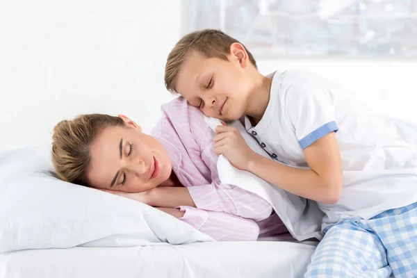 Adorable pequeño hijo abrazando su durmiendo madre - foto de stock