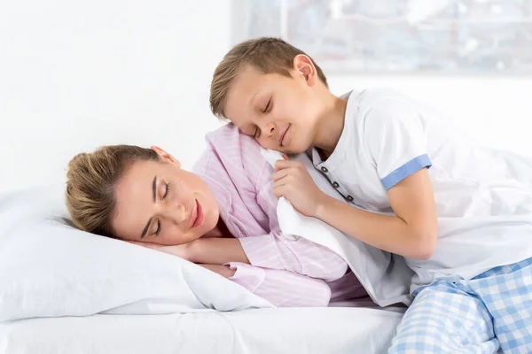 Adorabile piccolo figlio che abbraccia la madre addormentata — Foto stock