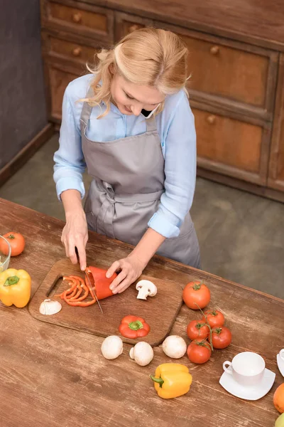 High angle view of woman talking by smartphone while cutting vegetables — Stock Photo