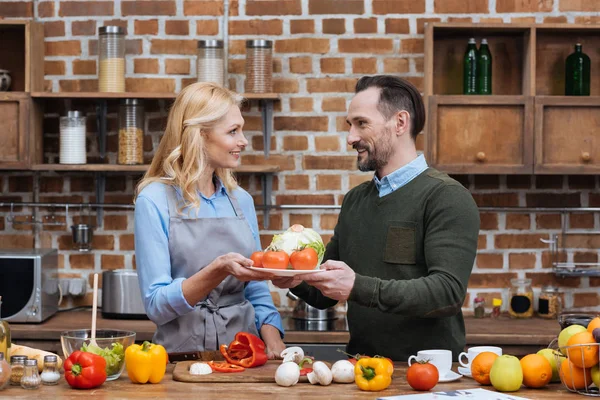 Mann schenkt Frau Teller mit Gemüse — Stockfoto