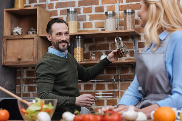 Lächelnder Ehemann schlägt Ehefrau Gewürze in Küche vor — Stockfoto