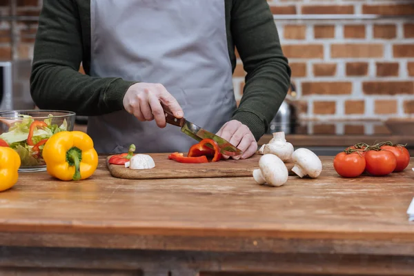 Cropped image of man cutting bell pepper in kitchen — Stock Photo