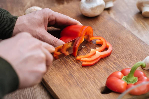 Обрізане зображення людини, що ріже болгарський перець на кухні — стокове фото