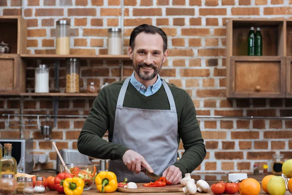 Hombre guapo cortar verduras en la cocina - foto de stock