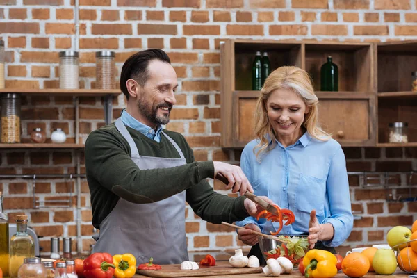 Feliz pareja preparando ensalada en la cocina - foto de stock