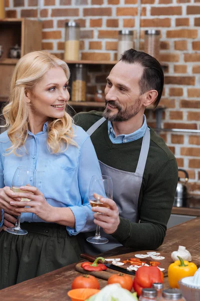Husband and wife with glasses of wine in kitchen — Stock Photo