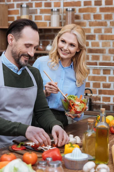 Feliz marido y esposa cocinando juntos en la cocina - foto de stock