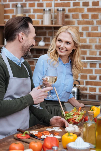 Smiling husband and wife clinking with glasses of wine — Stock Photo