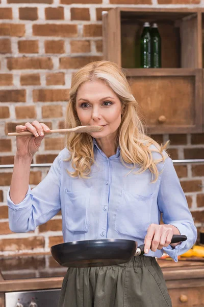 Frau probiert Essen aus Holzspachtel — Stockfoto