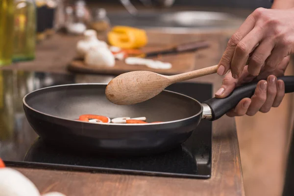 Cropped image of woman holding wooden spatula and frying pan — Stock Photo