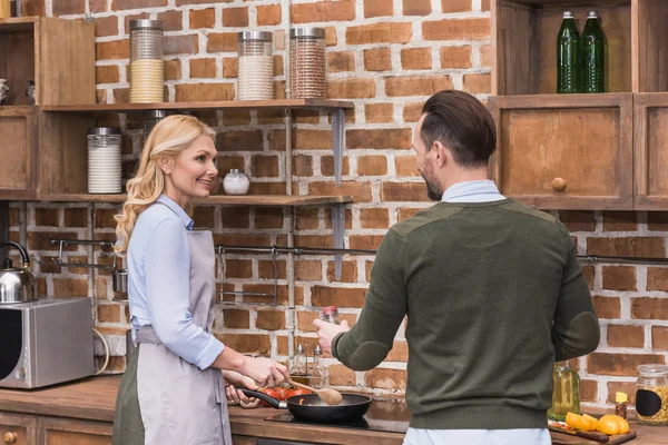 Жена и муж готовят на кухне и смотрят друг на друга — стоковое фото