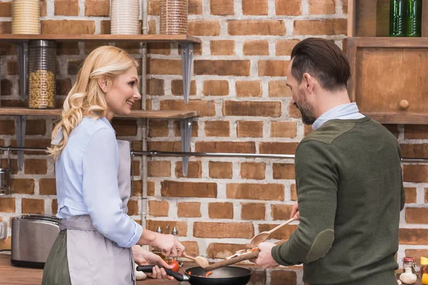 Esposa y marido cocinando juntos en la cocina - foto de stock
