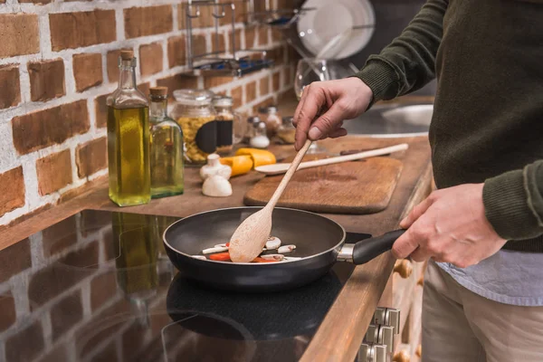 Imagen recortada del hombre revolviendo verduras en la sartén - foto de stock