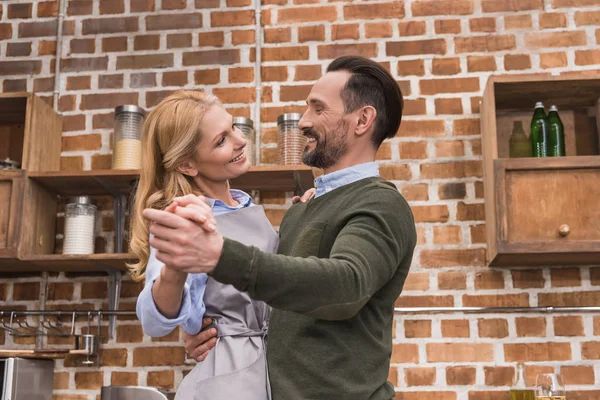 Sonriente esposa y marido bailando en la cocina - foto de stock