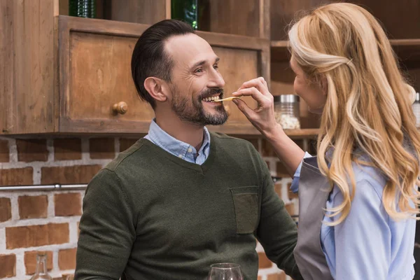 Wife giving husband to bite piece of cheese — Stock Photo