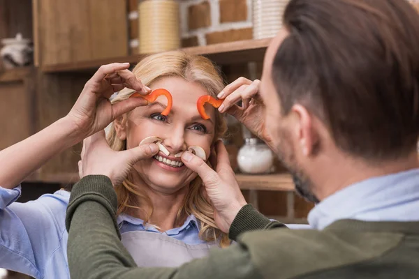 Wife and husband having fun and grimacing with pieces of vegetables — Stock Photo