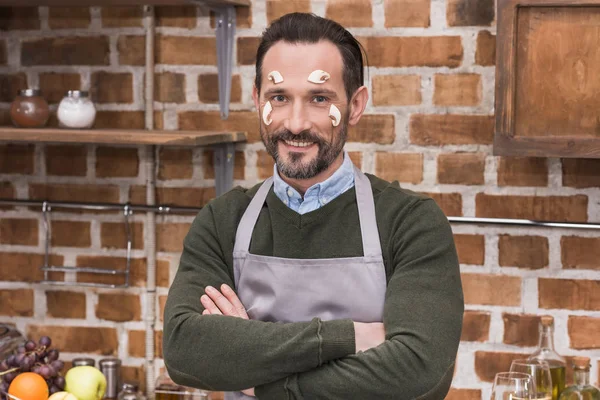 Smiling man with mushrooms on face looking at camera with crossed arms — Stock Photo