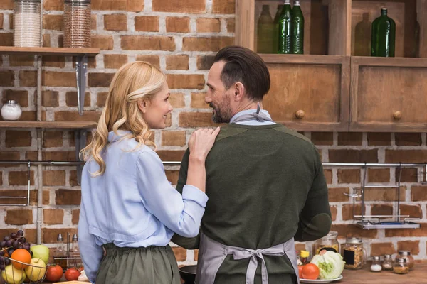 Moglie abbracciare marito mentre cucina in cucina — Foto stock