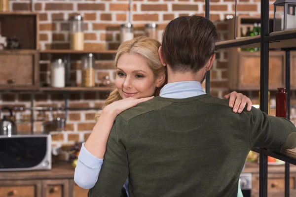 Attractive wife hugging husband in kitchen — Stock Photo