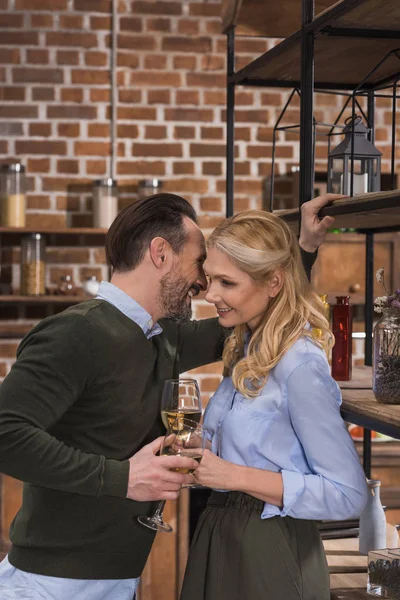 Marido diciendo algo a la esposa y sosteniendo vasos de vino - foto de stock