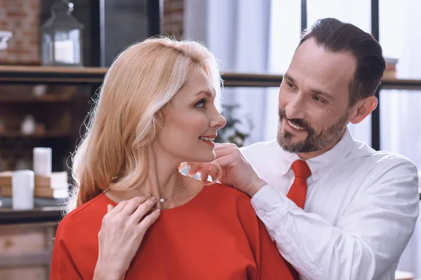 Sonriente marido con collar en el cuello de la esposa, San Valentín concepto de día - foto de stock