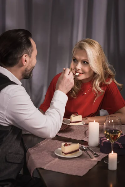 Husband feeding wife with piece of cake — Stock Photo