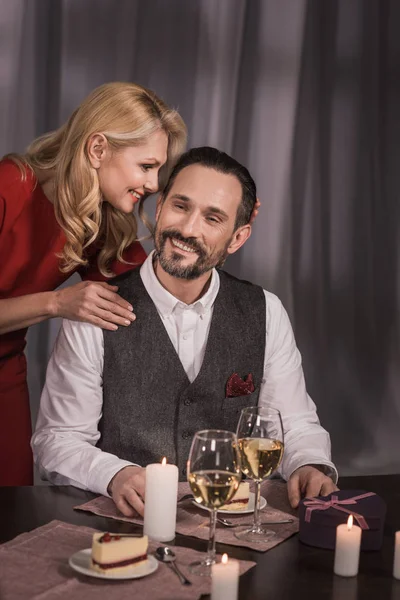 Wife hugging husband and saying something during dinner — Stock Photo