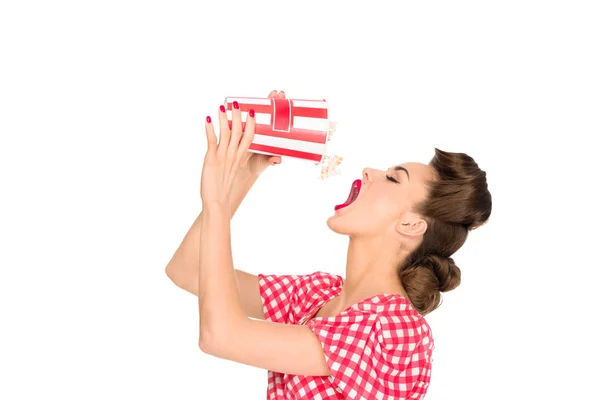 Vista lateral de la mujer joven con estilo comer palomitas de maíz aislado en blanco - foto de stock