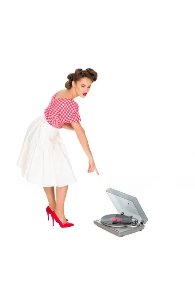 Woman in pin up style clothing pointing at phonograph isolated on white — Stock Photo