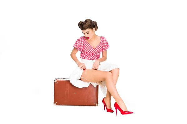 Красивая молодая женщина в ретро-одежде сидит на чемодане изолированы на белом — стоковое фото