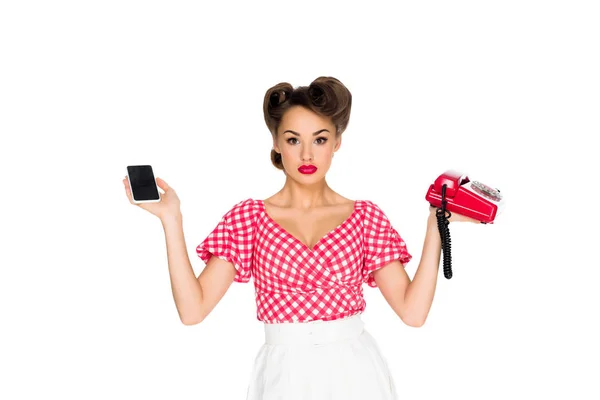 Retrato de mulher elegante em roupas retro segurando smartphone e telefone antigo isolado em branco — Fotografia de Stock