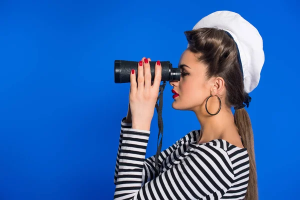 Side view of attractive young woman in retro clothing with binoculars isolated on blue — Stock Photo