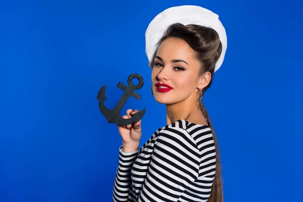 Portrait of fashionable young woman in retro clothing with anchor in hand isolated on blue — Stock Photo