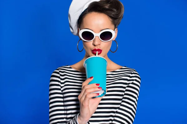 Ritratto di giovane donna elegante con bevanda in tazza di carta isolata su blu — Foto stock