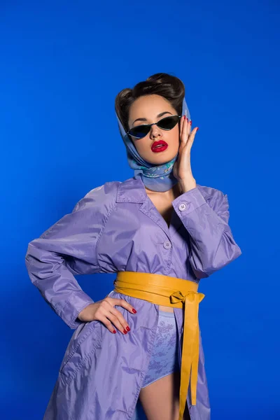 Retrato de mujer con estilo en ropa retro y gafas de sol aisladas en azul - foto de stock