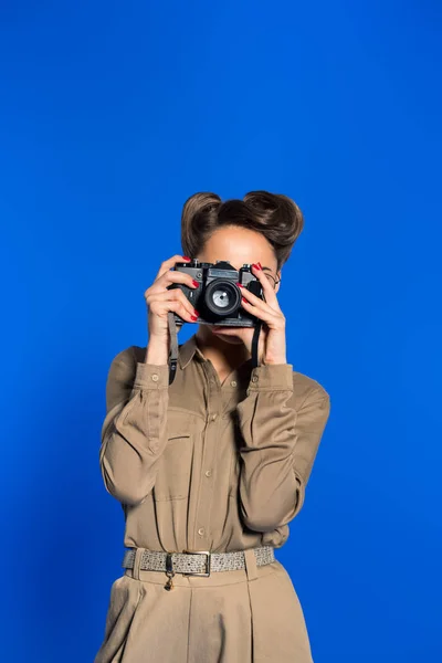 Visão obscurecida de mulher jovem na moda em roupas retro com câmera fotográfica isolada em azul — Fotografia de Stock