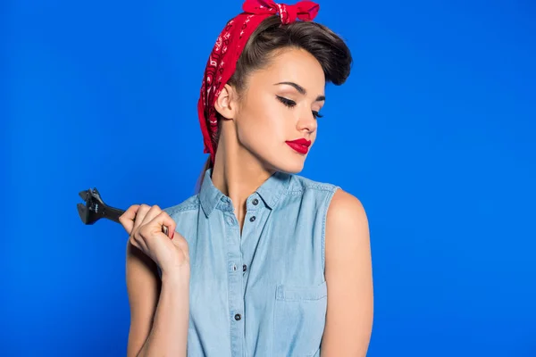 Модна молода жінка в одязі в стилі шпильки з гайковим ключем ізольовано на синьому — стокове фото
