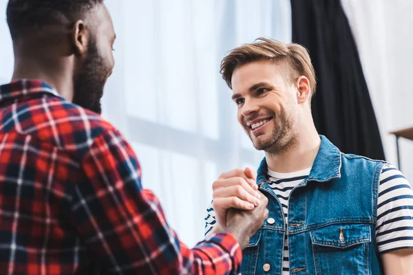 Selective focus of young multiethnic men smiling each other — Stock Photo