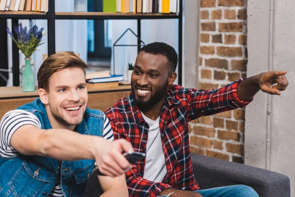 Lächelnde junge multiethnische Freunde, die gemeinsam fernsehen — Stockfoto