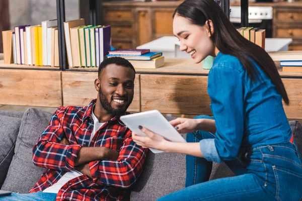 Glückliches junges multiethnisches Paar mit digitalem Tablet zu Hause — Stockfoto