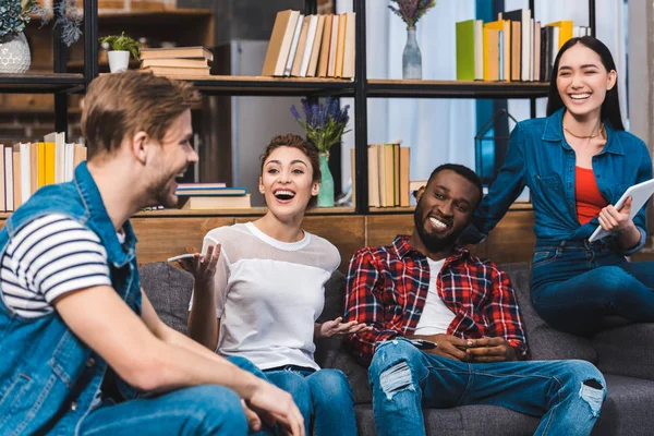 Glückliche junge multiethnische Freunde, die gemeinsam digitales Tablet und Smartphone nutzen — Stockfoto