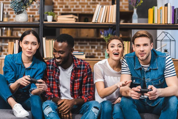 Glückliche junge multiethnische Freunde, die zu Hause gemeinsam mit Gamepads spielen — Stockfoto