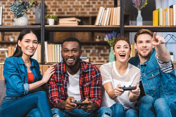 Excité jeunes amis multiethniques jouer avec joysticks ensemble à la maison — Photo de stock