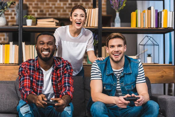 Happy young multiethnic friends playing with joysticks together — Stock Photo