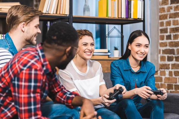 Happy young multiethnic friends playing with joysticks together at home — Stock Photo